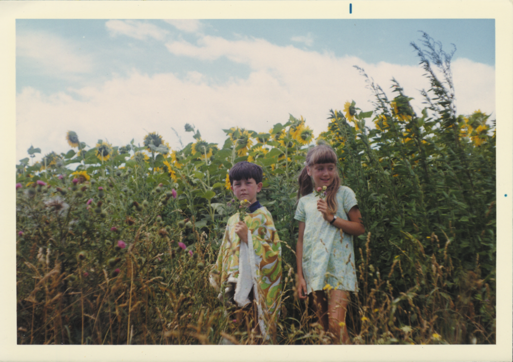 Sunflower Kids - Photograph of children in sunflower field wearing ponchos.